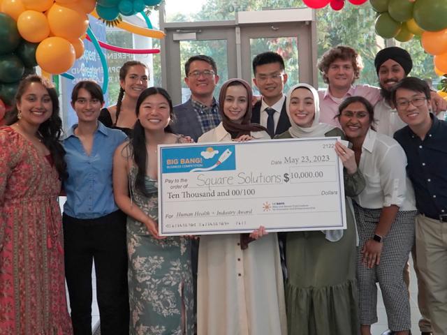 group of young students with a large check