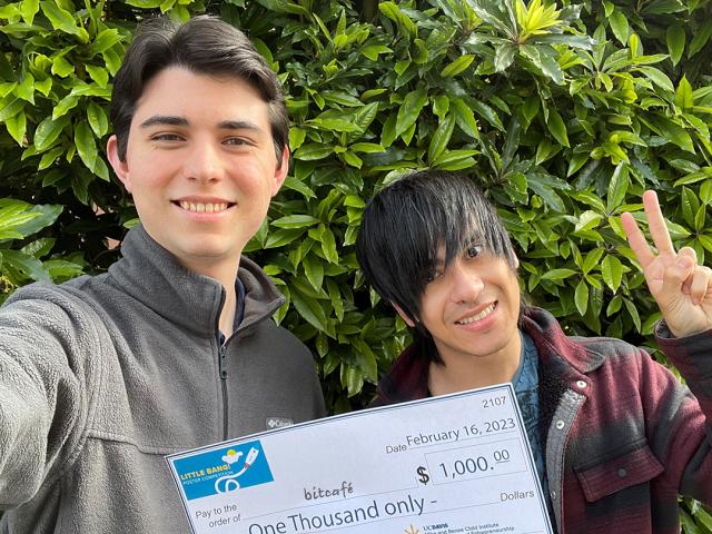 two undergraduates with a large check